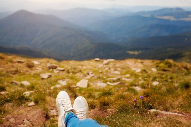 Karpat dağlarında yürüyüş. Yürüyüş yapan kadın çimlerin üzerinde uzanarak manzaranın tadını çıkarıyor. Yazın Ukrayna 'da seyahat. Ayakkabılarınızı kapatın.