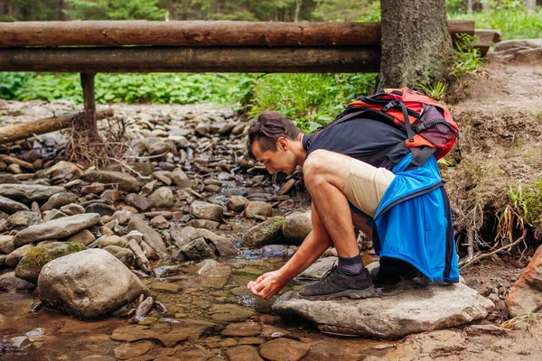 在喀尔巴阡山脉的森林里，背负背包的旅行者想通过桥喝水洗脸. — 图库照片