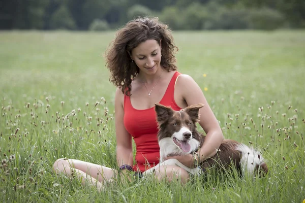 Cane e donna in un prato — Foto Stock