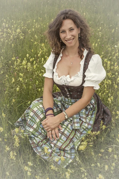 Frau mit Dirndl in Blumenwiese — Stock fotografie