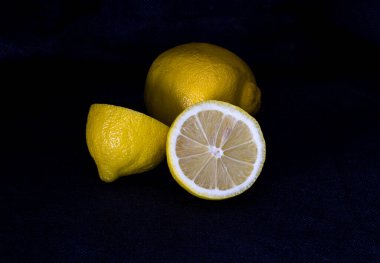 Koyu arkaplanda dilimlenmiş limon, yarım limon.