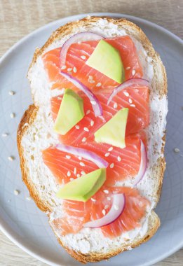 Somonlu sandviç, süzme peynir, avokado, kırmızı soğan ve susam tohumları. Sağlıklı kahvaltı.