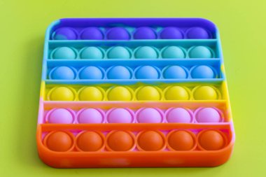 Stres önleyici oyuncağı yeşil arka plana yerleştir. Renkli silikon oyuncak, kabarcık kıpırtı, basit gamze