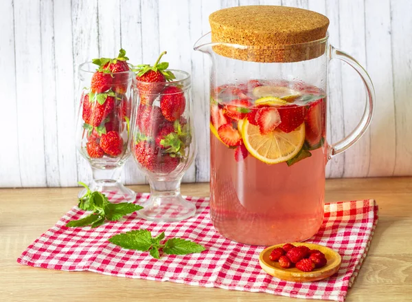 Jahodová a mátová limonáda ve skleněném džbánu s korkovým víčkem, čerstvé jahody ve sklenicích — Stock fotografie