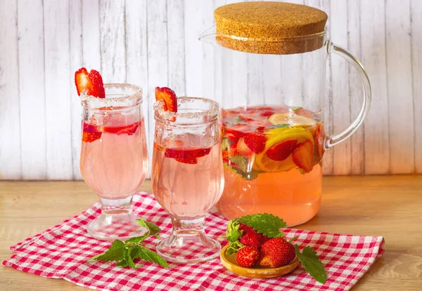 Strawberry and mint lemonade in two glasses and a glass jug — стоковое фото
