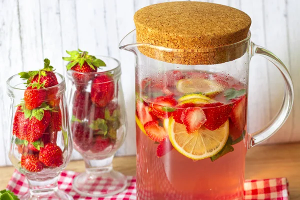 Jahodová a mátová limonáda ve skleněném džbánu s korkovým víčkem, čerstvé jahody ve sklenicích — Stock fotografie