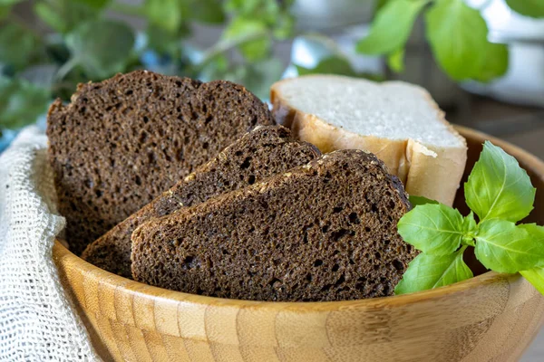 Sliced rye bread in a wooden bowl and a sprig of basil — Foto de Stock