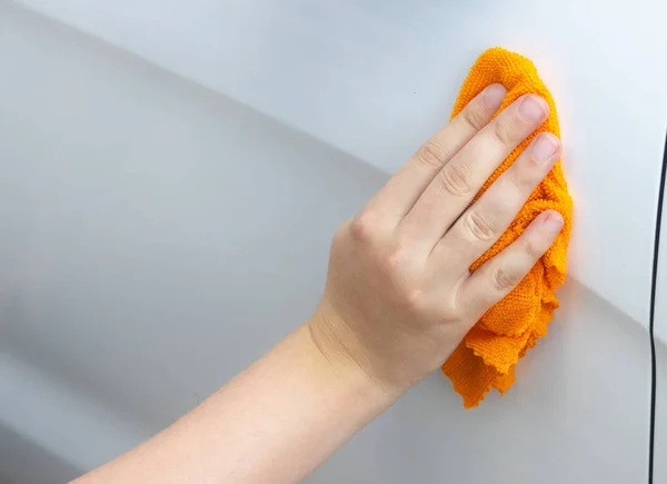 La main lave la voiture avec un chiffon orange Images De Stock Libres De Droits