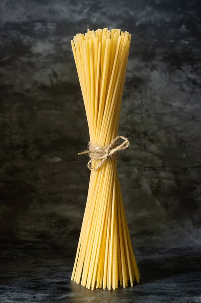 Espaguete Cru Está Sobre Fundo Escuro Amarrado Com Uma Corda — Fotografia de Stock