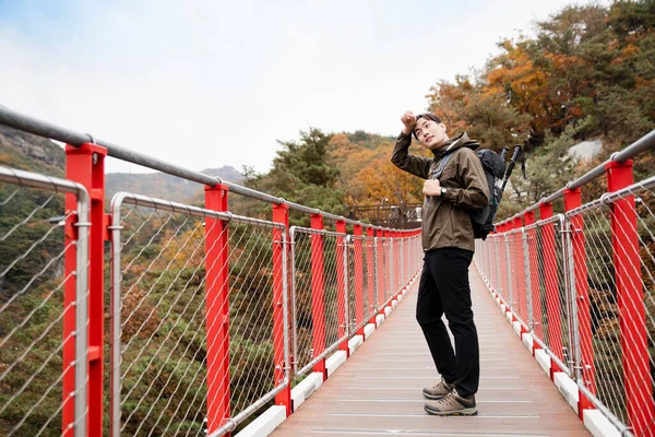 Asian handsome man with mask trekking, climbing autumn mountain