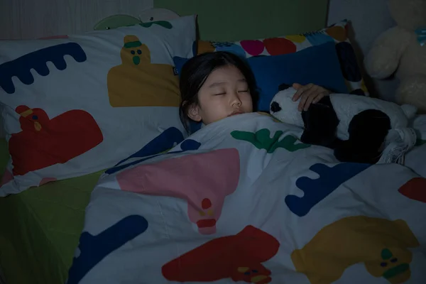 Asian girl sleeping in room with lights off