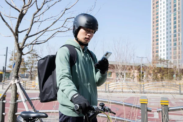 bike delivery service man checking order location with phone