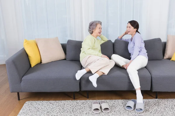 happy smiling Asian old mother and middle aged daughter on sofa