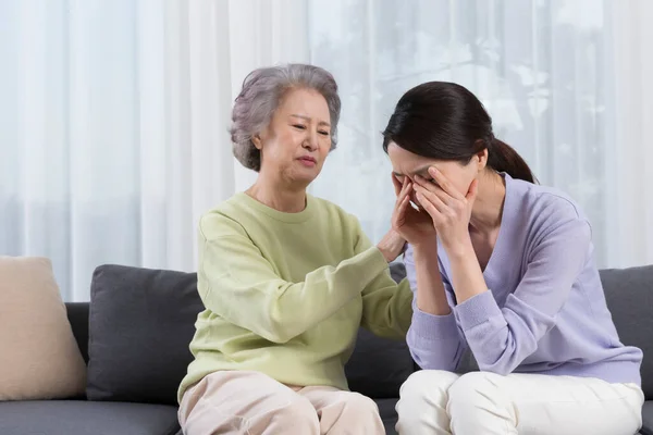 Asian old mother comforting depressed middle aged daughter