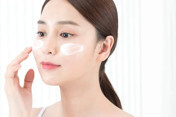 Beautiful Asian model face with facial lotion cream, skin beauty concept
