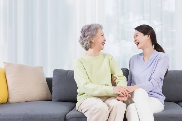 happy smiling Asian old mother and middle aged daughter on sofa