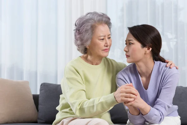 Asian old mother comforting depressed middle aged daughter