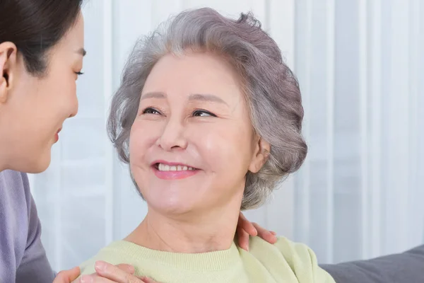 happy smiling Asian old mother and middle aged daughter on sofa