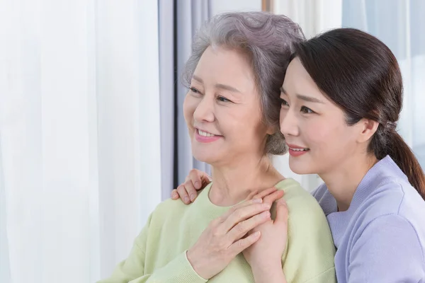 happy smiling Asian old mother and middle aged daughter on sofa