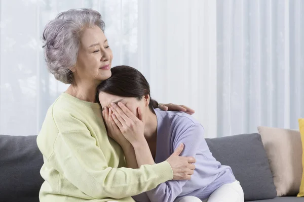 Asian old mother comforting depressed middle aged daughter