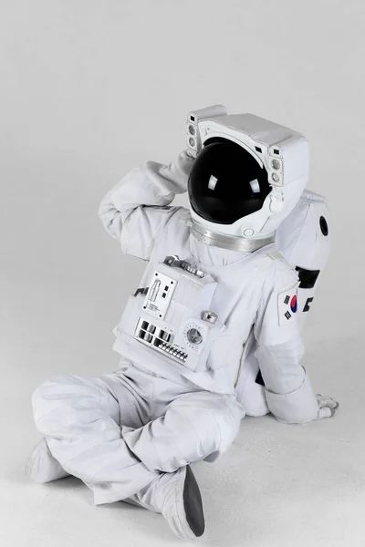 Astronaut scratching the back of the head, white background