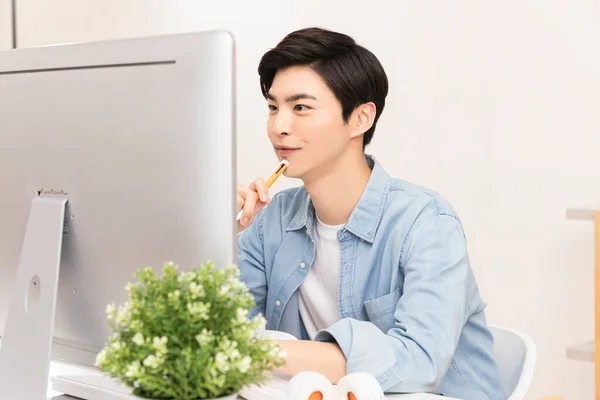 若いアジア系韓国人の男性がコンピュータモニタに焦点を当て — ストック写真