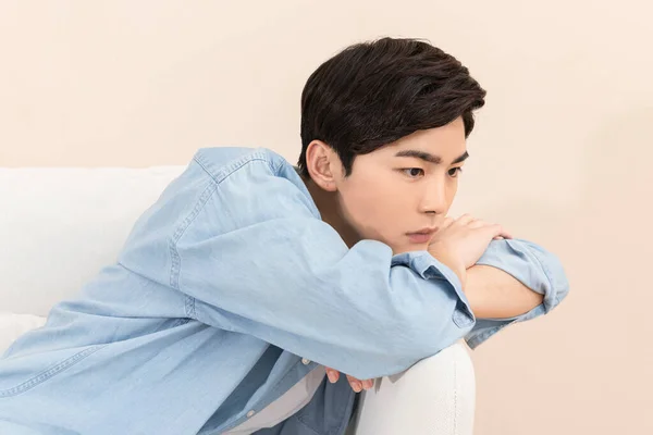 Deprimido Asiático Hombre Joven Sentado Interior Sofá —  Fotos de Stock