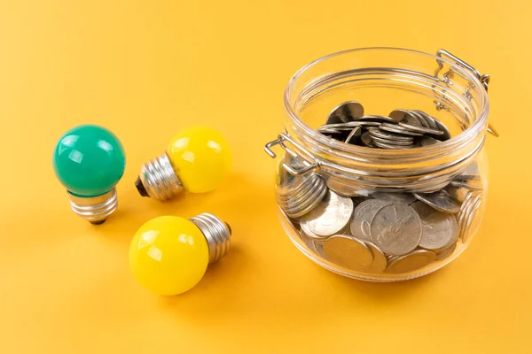 緑のミニ電球と黄色の背景にコイン エコエネルギーの概念 — ストック写真