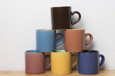 Tahta tabanda farklı renklerde altı kahve fincanı piramidi.