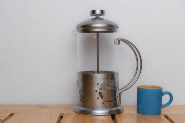 pompa kahve makinesi ve ahşap tabanda mavi bardak ve beyaz sırt.