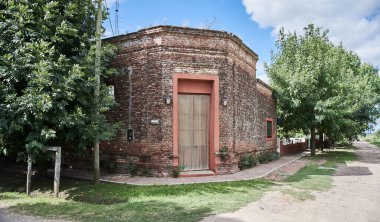 Köşesinde tuğla kapılı ve pencereli eski bir kır evi var.