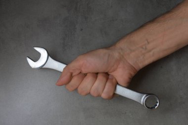 Gri arkaplanda el ele tutuşan metalik anahtar