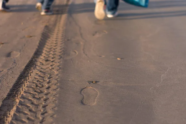 鞋和车辙在沙滩上 人们的脚在远方 — 图库照片