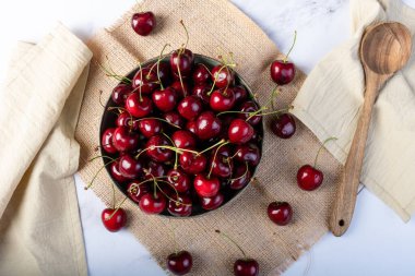 Taze kırmızı kirazlarla dolu bir kasenin üst görüntüsü.