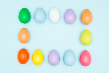 Pastel arka plan karede düzenlenen renkli Paskalya yumurtaları