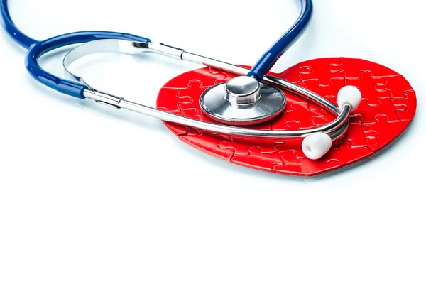 Corazón rompecabezas rojo con estetoscopio aislado sobre fondo blanco — Foto de Stock