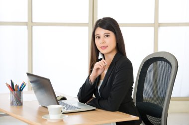 Dizüstü bilgisayar ve içecek kahve masasında kullanarak Asya girişimci gülümseyen