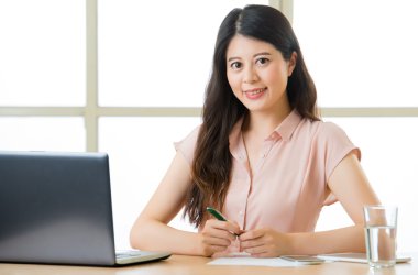 Oturma ve masa başında gülümseyen başarılı Asyalı kadın girişimci