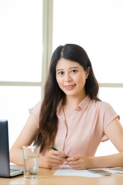 Oturma ve masa başında gülümseyen başarılı Asyalı kadın girişimci