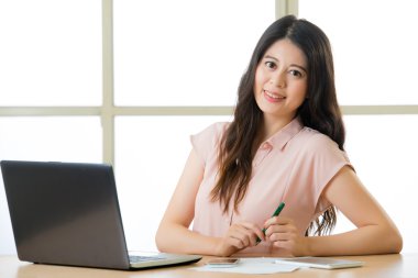 Yazma ve masa başında gülümseyen başarılı Asyalı kadın girişimci