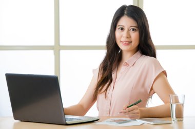 Yazma ve masa başında gülümseyen başarılı Asyalı kadın girişimci
