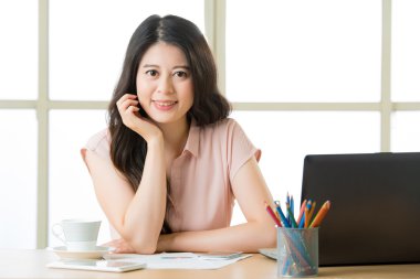 Oturma ve masa başında gülümseyen başarılı Asyalı kadın girişimci