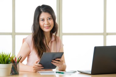 Mutlu genç Asyalı kadın masada tablet kullanma