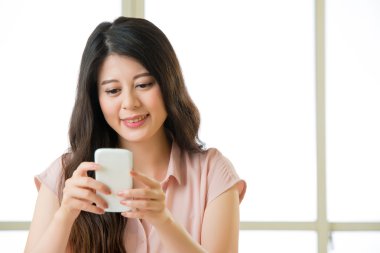 Mutlu genç Asyalı kadın akıllı telefon kısa mesaj kullanarak