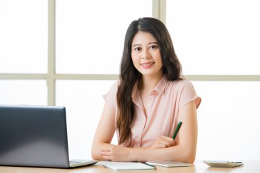 Oturma ve masa başında gülümseyen başarılı Asyalı kadın girişimci