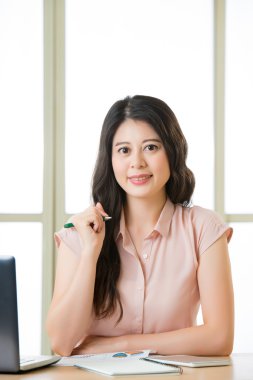 Oturma ve masa başında gülümseyen başarılı Asyalı kadın girişimci