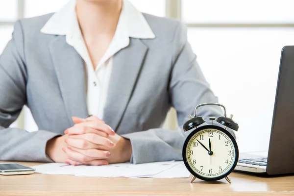 Asiatische Geschäftsfrau sitzt am Schreibtisch mit Wecker — Stockfoto