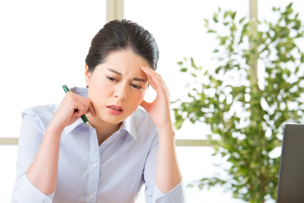 Jonge Aziatische zakenvrouw schrijven met hoofdpijn — Stockfoto