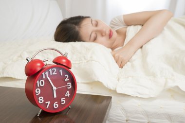 çalar saat yanındaki yatakta uyuyan kadın