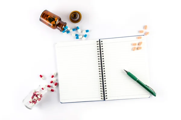 Capsules and bottle with notebook and pen, prescription — Stock Photo, Image